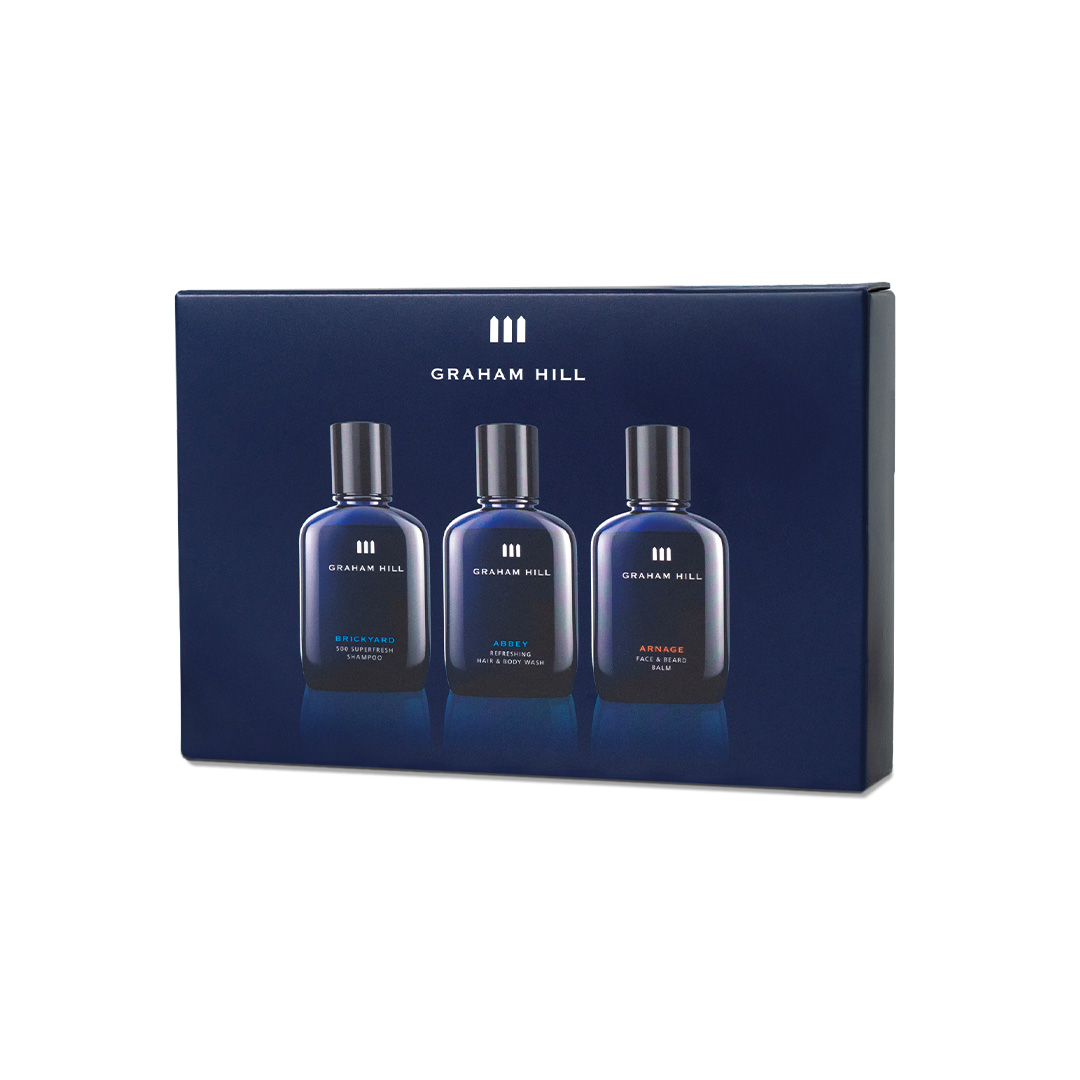 Dunkelblaue Geschenkverpackung des GRAHAM HILL TRAVEL SET mit BRICKYARD Shampoo, ABBEY Hair & Body Wash und ARNAGE Face & Beard Balm in je 100 ml.